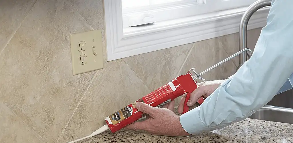 Handyman applying caulk along a kitchen backsplash and countertop seam in Scottsdale, AZ