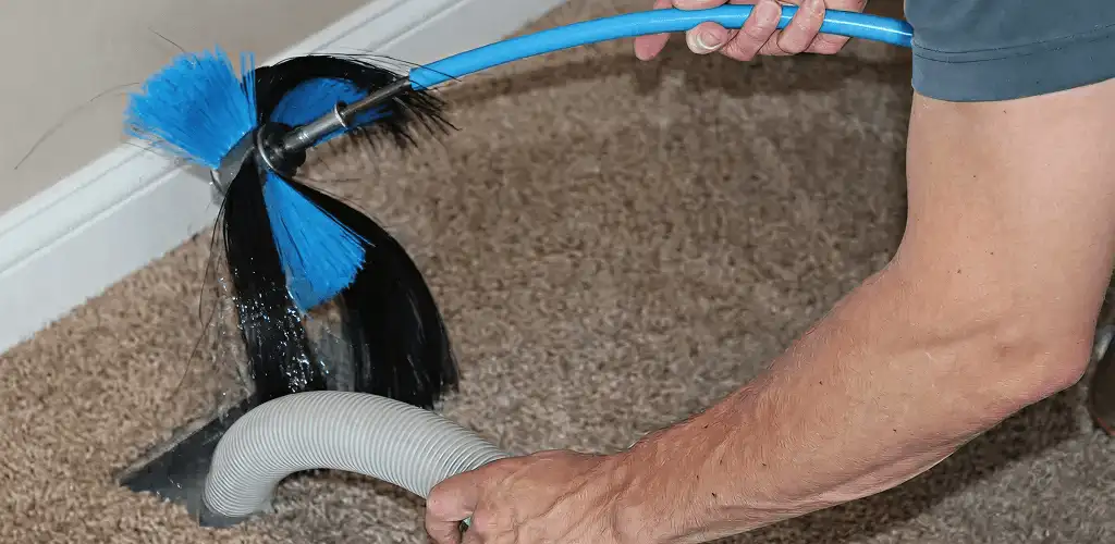 Dryer vent cleaning technician brushing lint from a vent line in Scottsdale, AZ