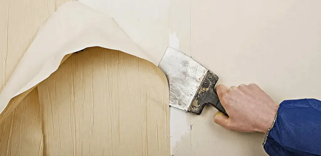 Handyman removing wallpaper with a scraper for wall preparation in Scottsdale, AZ